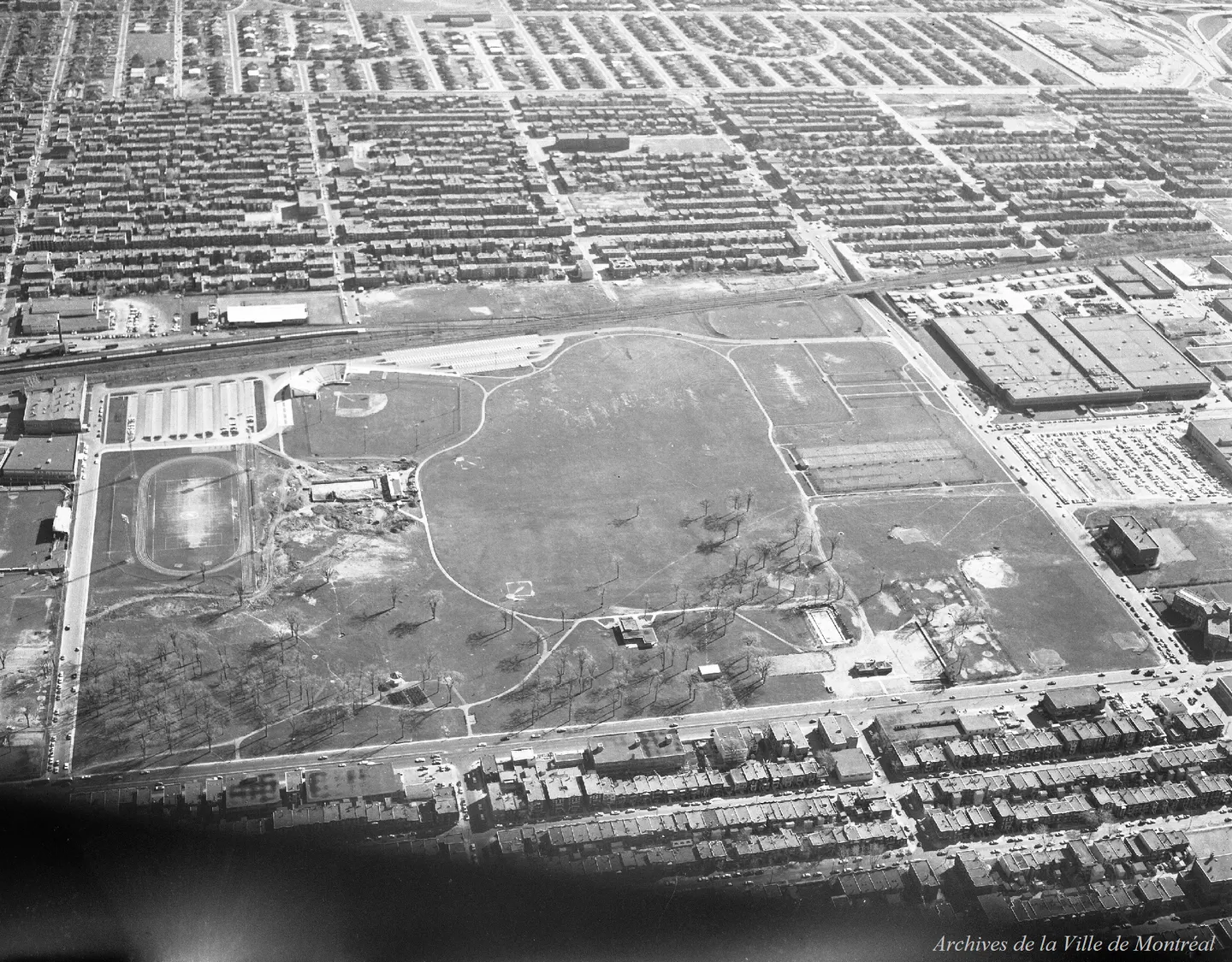 Terrain de baseball, bâtiments autour, voitures garées, vue aérienne