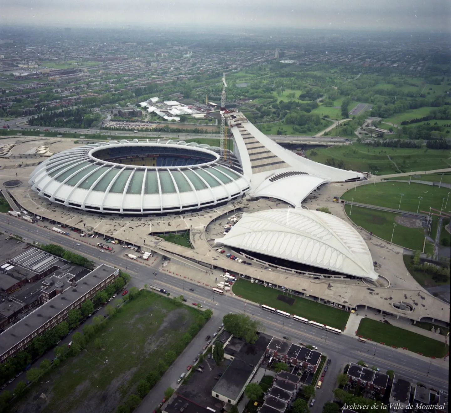 Stade olympique avec toit en dôme, voitures et piétons dans la rue