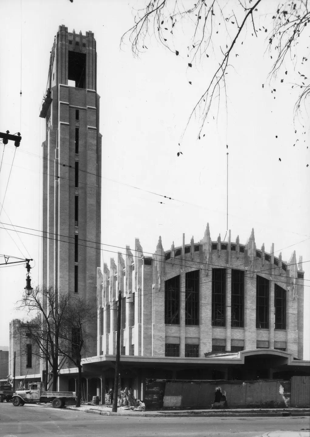 Photo en noir et blanc d'un bâtiment de Montréal avec une grande tour d'horloge, situé à côté d'une rue.